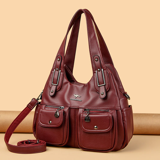 Red handbag with multiple pockets and a strap on a beige background