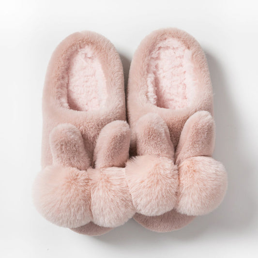 Pair of pink fluffy slippers with bunny ears on a light gray background