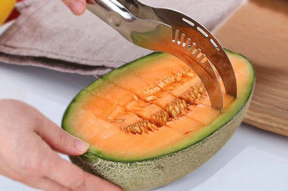 Person using a melon baller to scoop out a cantaloupe on a white surface.