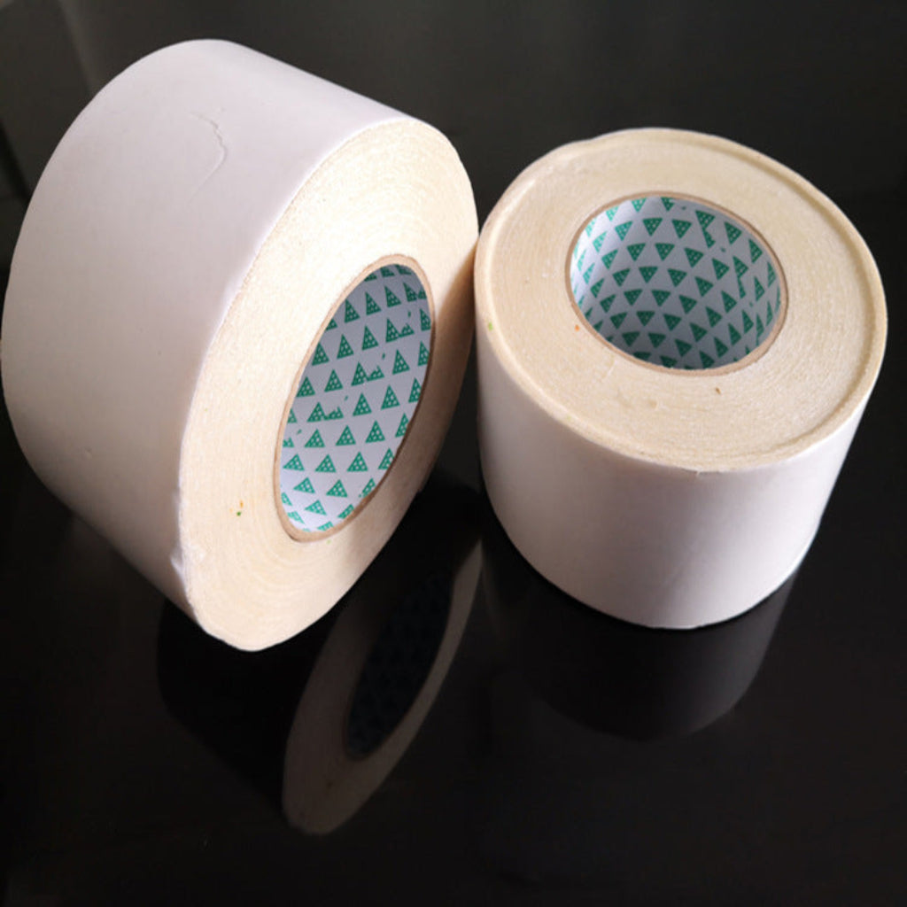 Two rolls of white tape with green pattern on a black background