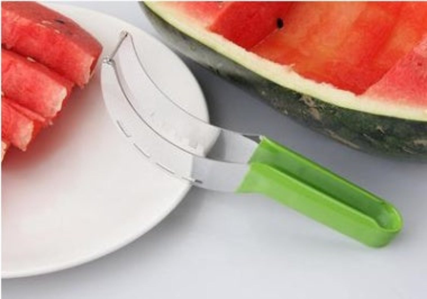 Watermelon slicer with a green handle on a white surface next to a sliced watermelon.