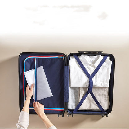 Person packing a suitcase with clothes and a folder, on a neutral background