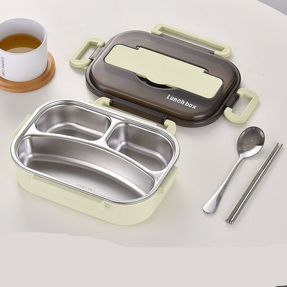 Green lunch box with compartments, spoon, and chopsticks on a white surface.