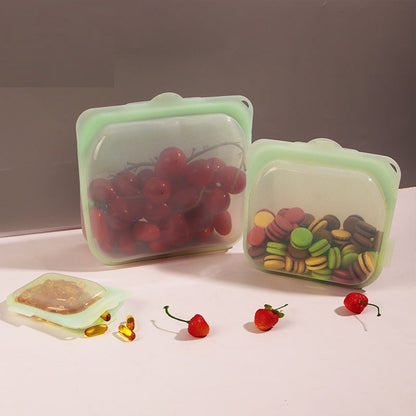 Silicone food containers with fruits and candies on a neutral background