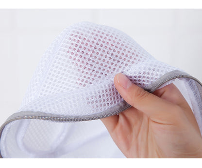 Hand holding a white mesh product with gray trim against a light background