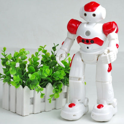 White and red robot toy standing next to a small green plant on a white background