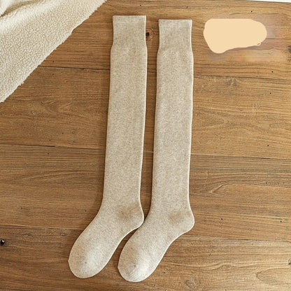 Pair of oatmeal-colored knee-high socks on a wooden surface with 'Oat' text.