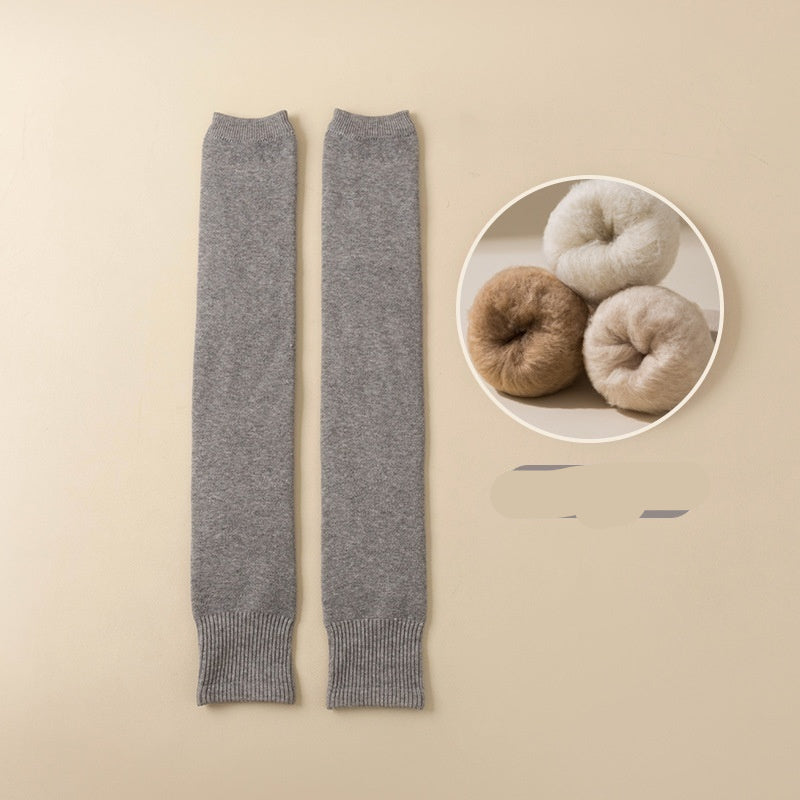 Light gray leg warmers on a beige background with a close-up of yarn balls in the corner.