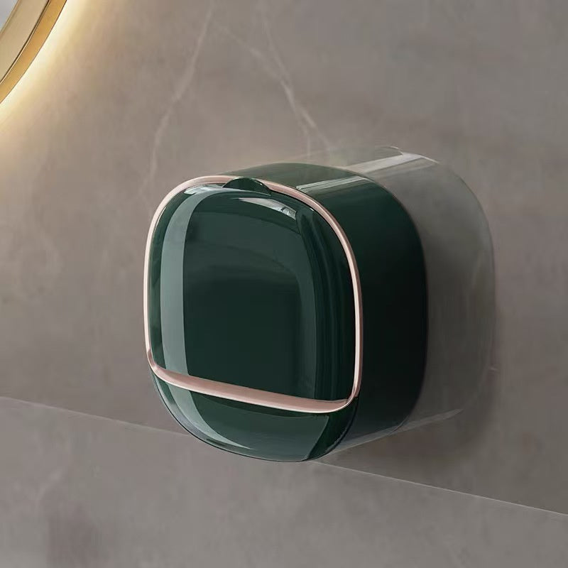 Green wall-mounted trash can with rose gold handle on a gray marble surface