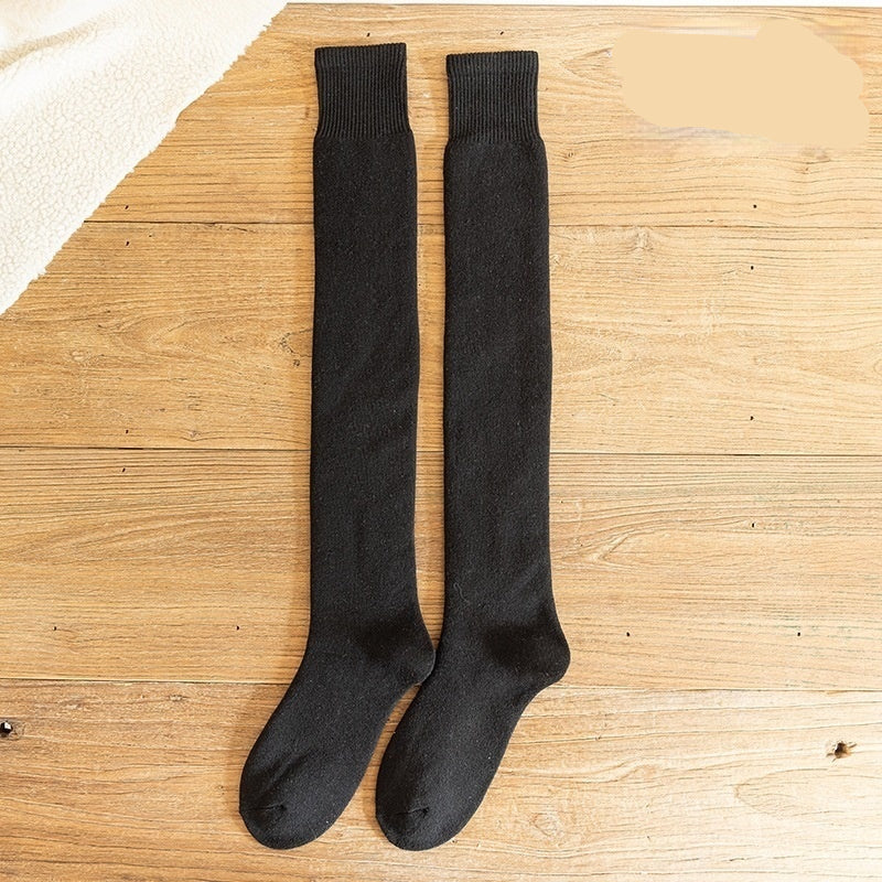 Black knee-high socks on a wooden surface with 'Black' text above.