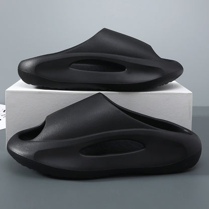 Two black slippers on a white rectangular block against a gray background
