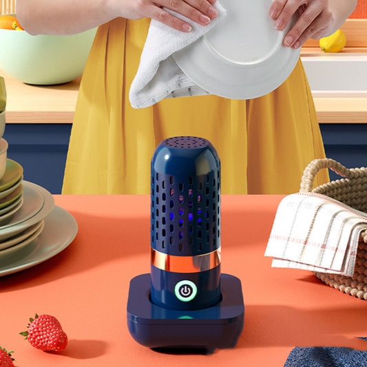 Blue and orange device on a table with a person cleaning dishes in the background