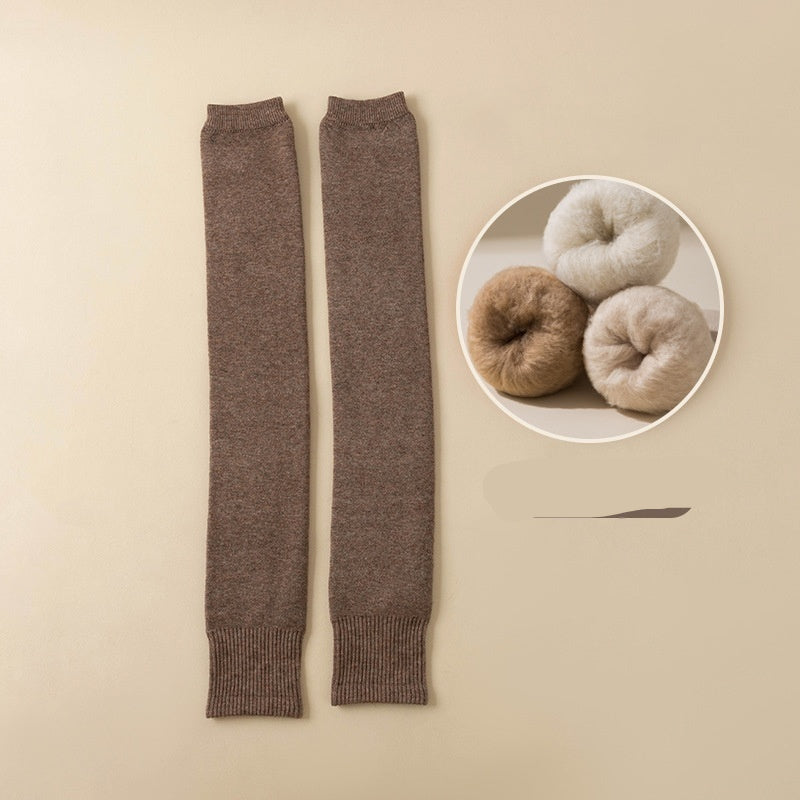 Dark brown leg warmers on a beige background with yarn balls in the corner.