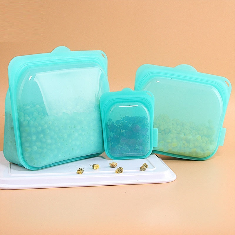 Set of teal silicone food storage bags on a beige background