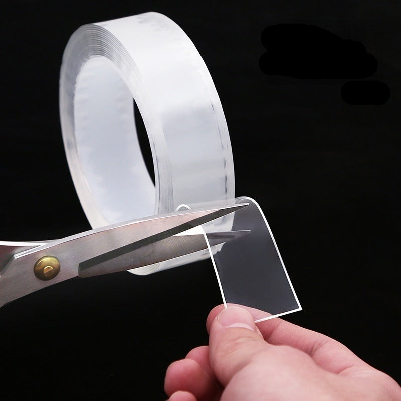 Clear tape with scissors and a hand holding a piece of clear material against a black background.