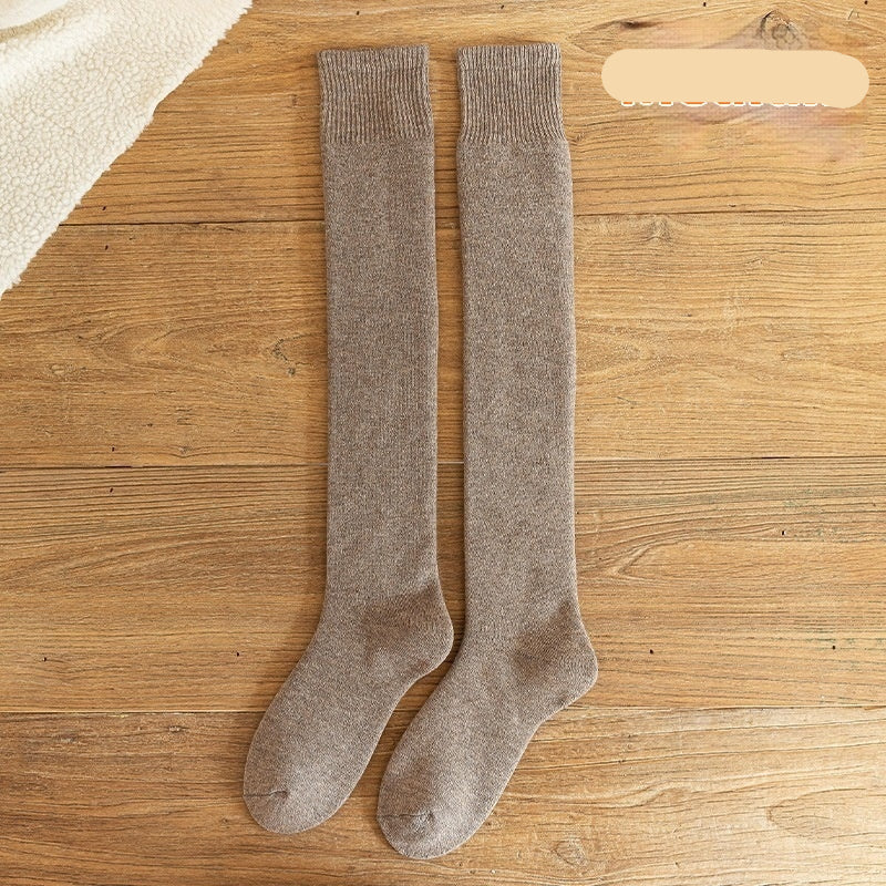 Pair of beige knee-high socks on a wooden surface with 'Medium' label.