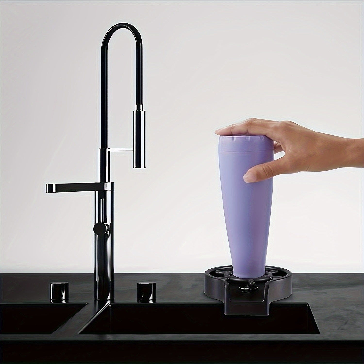 Purple cup being filled with water from a black faucet on a white background