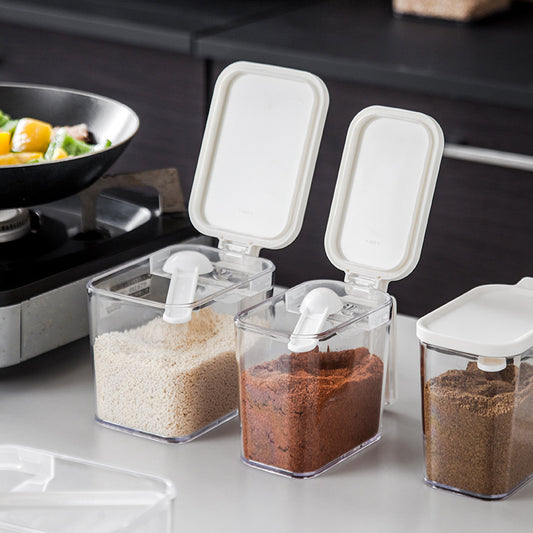 Three transparent spice containers with white lids on a kitchen counter.