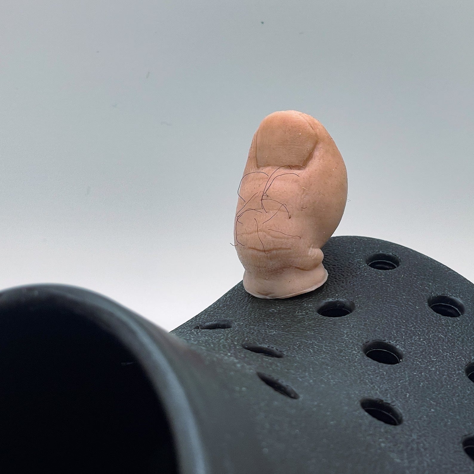 Model of a foot on top of a black object with a gray background