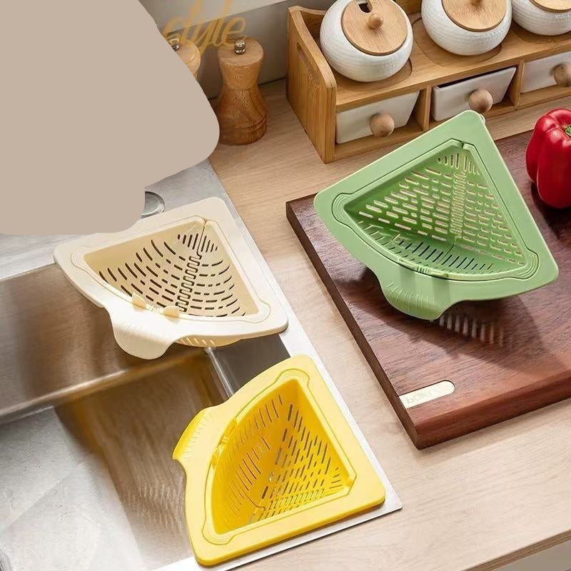 Kitchen scene with triangular drainer, yellow basket, and green strainer on a wooden surface.